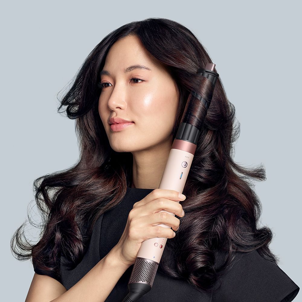 A blonde model styles her hair with the Dyson Airwrap Co-anda2x multi-styler.