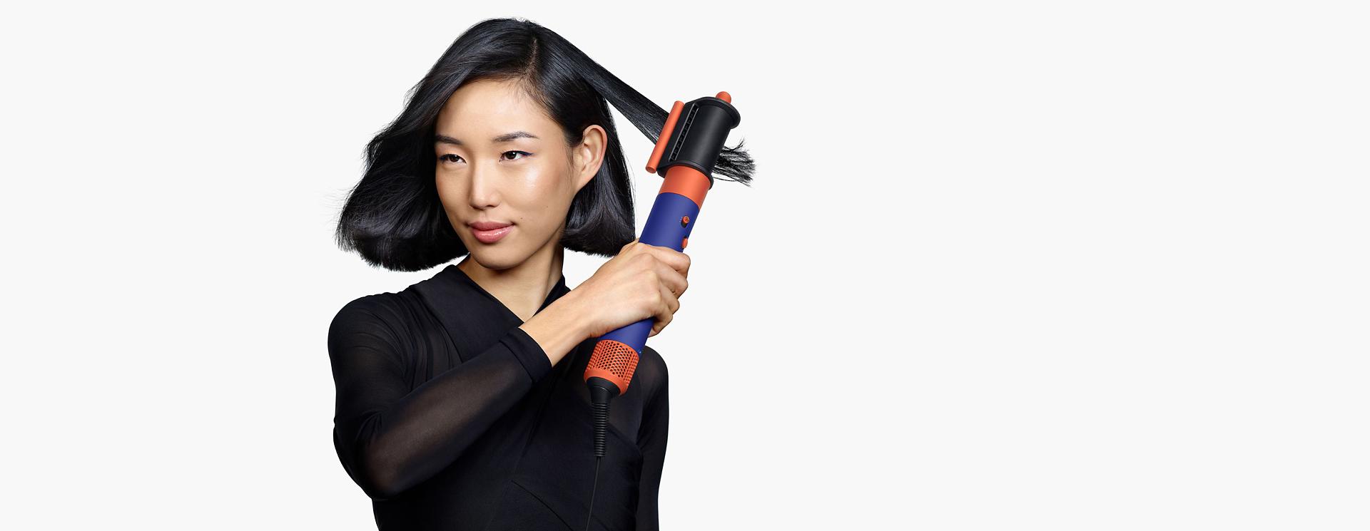 Model using the Dyson Airwrap i.d. multi-styler and dryer to style hair.