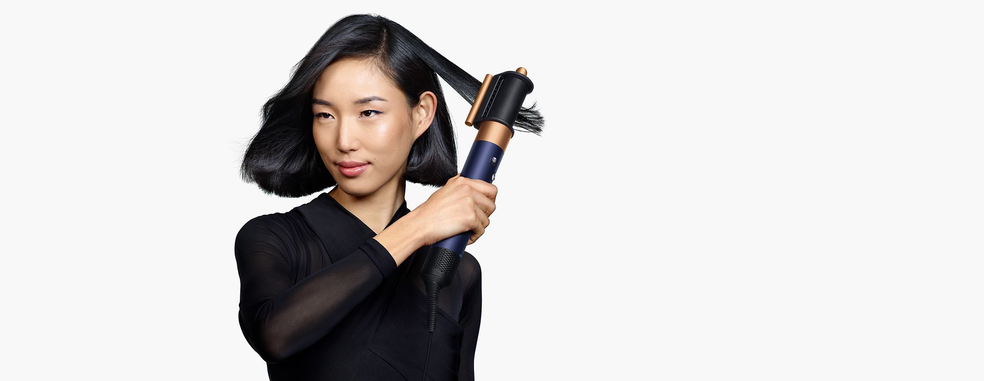 Model using the Dyson Airwrap i.d. multi-styler and dryer to style hair.