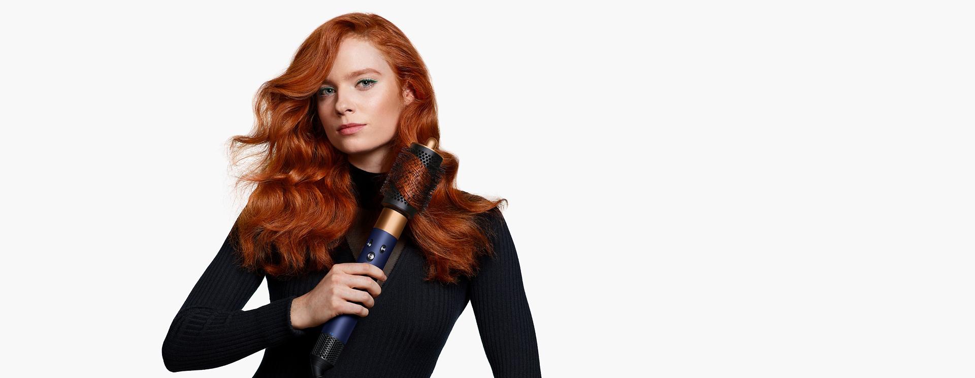 Model using the Dyson Airwrap i.d. multi-styler and dryer to style hair.
