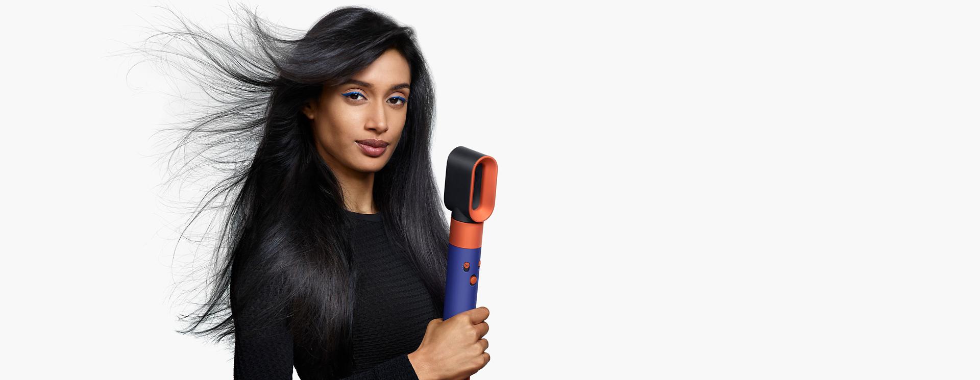 Model using the Dyson Airwrap i.d. multi-styler and dryer to dry hair.