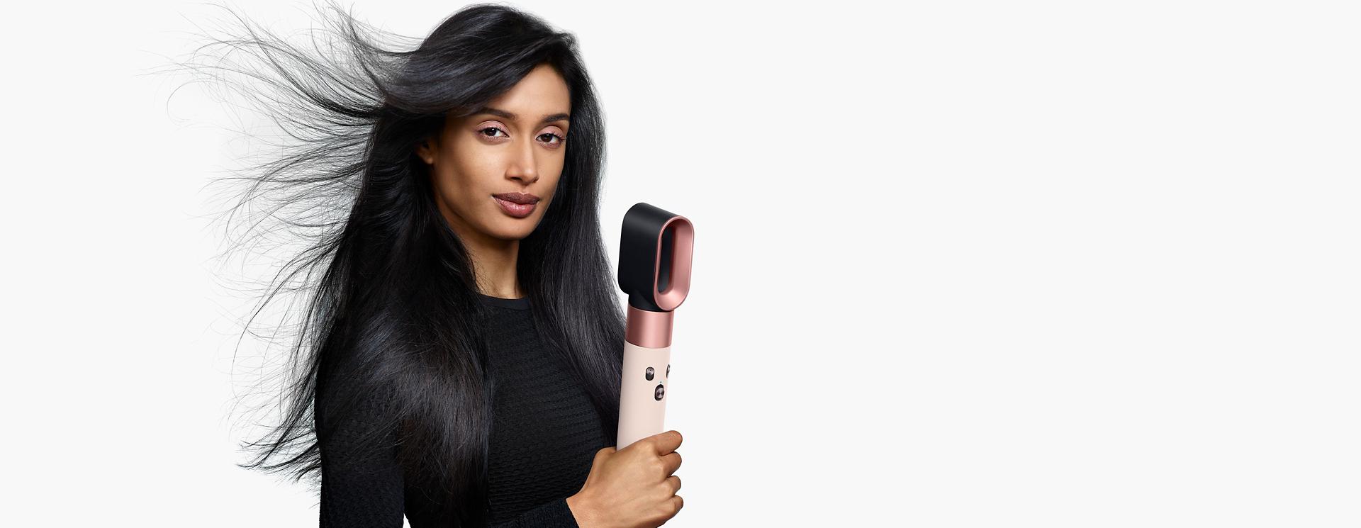 模特兒正在用 Dyson Airwrap i.d.™ 智能吹風造型器吹乾頭髮。