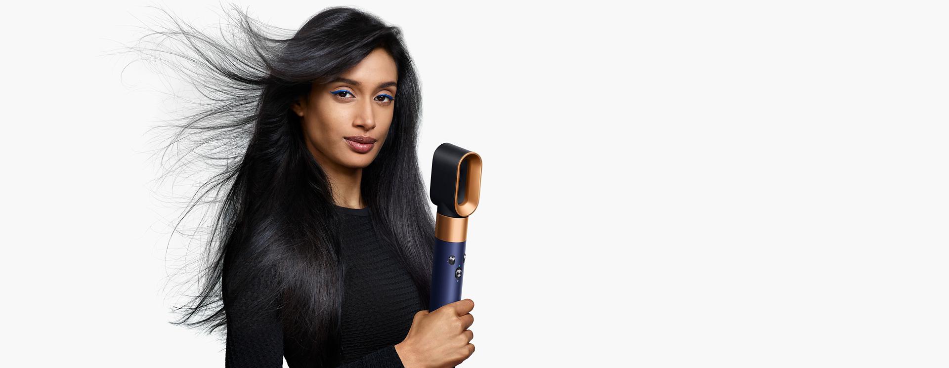Model using the Dyson Airwrap i.d. multi-styler and dryer to dry hair.