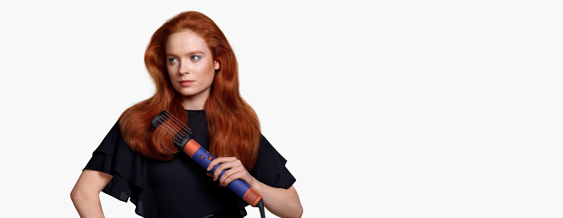 Model using the Dyson Airwrap i.d. multi-styler and dryer to curl hair.