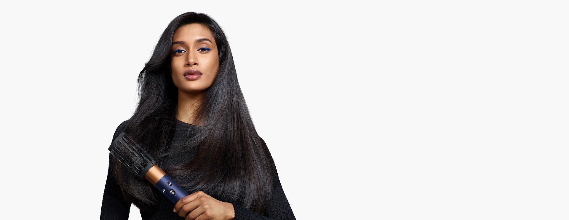 Model using the Dyson Airwrap i.d. multi-styler and dryer to curl hair.