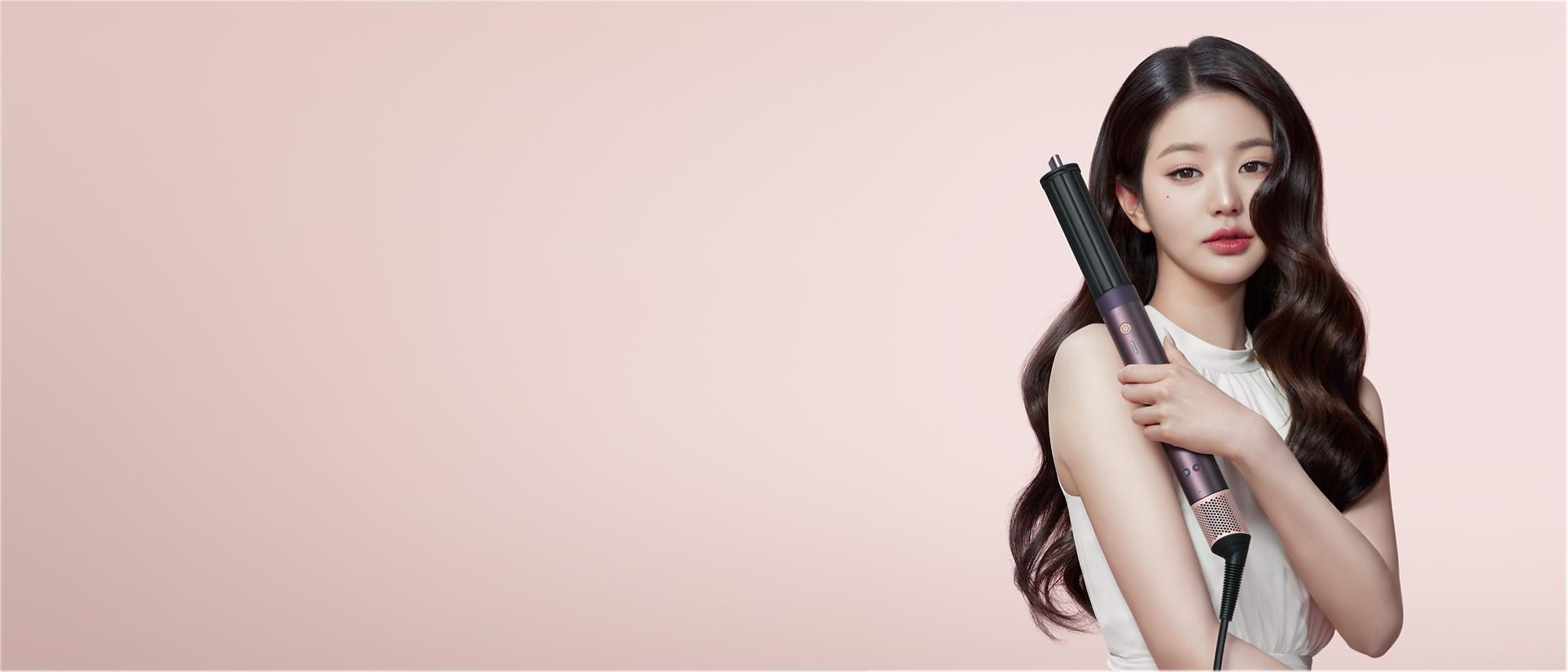 A model with dark hair adds curls using the Dyson Airwrap Co-anda2x multi-styler and dryer.