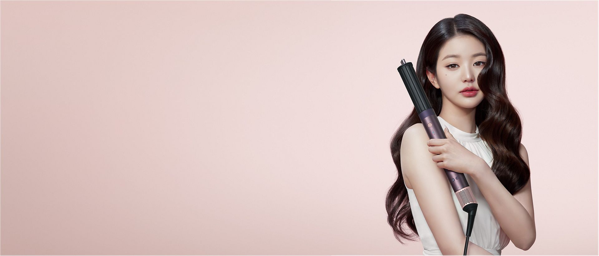 A model with dark hair adds curls using the Dyson Airwrap Co-anda2x multi-styler and dryer.