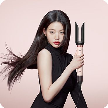 A blonde model straightens her hair using the Dyson Airwrap Co-anda2x multi-styler and dryer and the AirSmooth2x attachment.