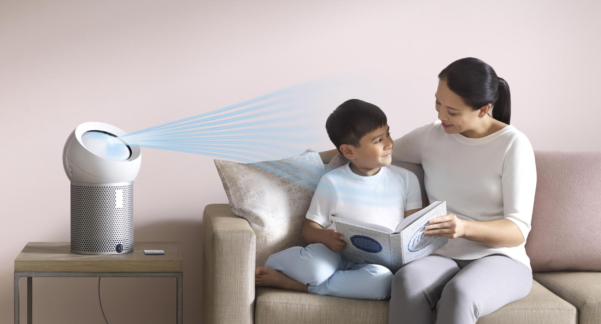A woman reads to her son, next to a Dyson personal purifier fan