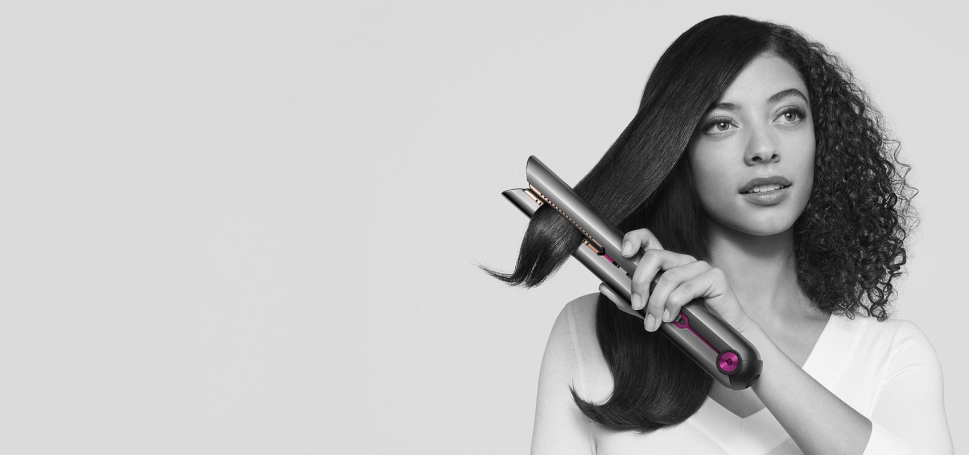 Woman achieving beautifully straight hair with the Dyson Corrale straightener