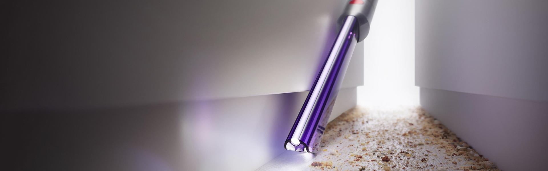 다이슨 틈새 라이트 브러시를 이용해 어두운 공간에서 청소하는 이미지