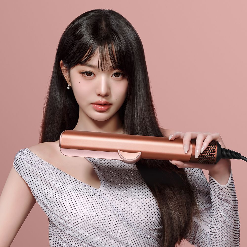 A model styles hair with the Dyson Airstrait.