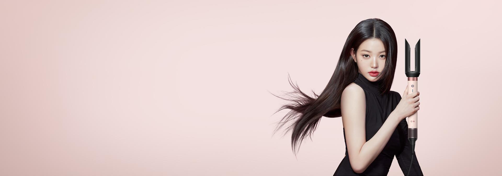 금발 머리에 에어스무스 2x™ 스타일링 툴로 다이슨 에어랩 코안다 2x™ 멀티 스타일러 앤 드라이어를 스타일링하고 있는 모델.