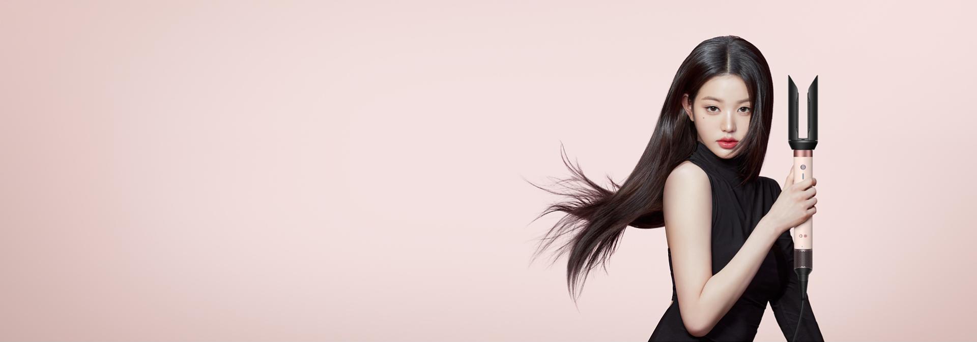 A blonde model straightens her hair using the Dyson Co-anda2x multi-styler and dryer and the AirSmooth2x attachment.