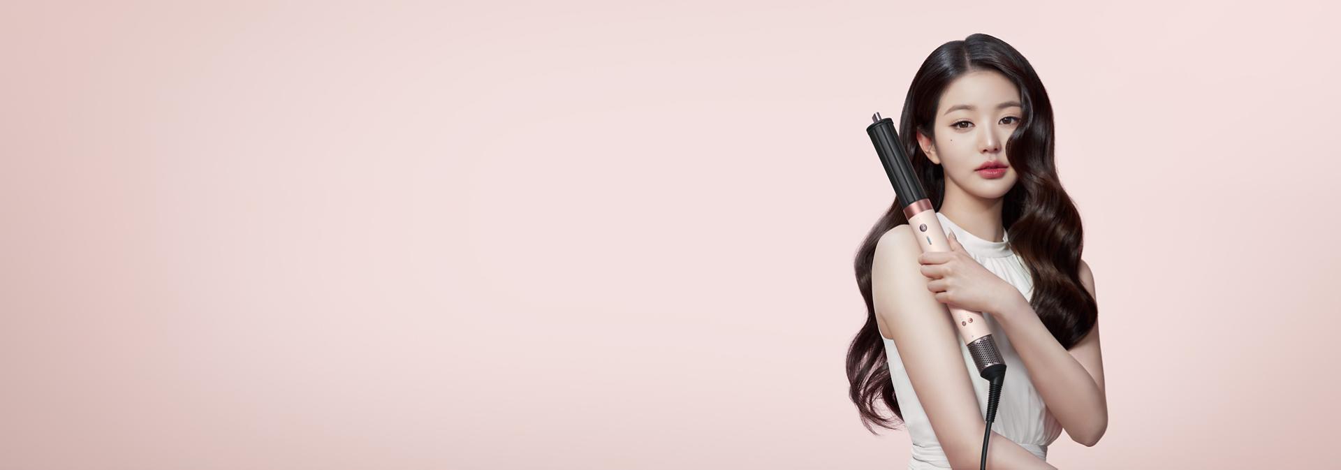 다이슨 에어랩 코안다 2x™ 멀티 스타일러 앤 드라이어를 사용해 컬을 추가하고 있는 검은색 모발의 모델.