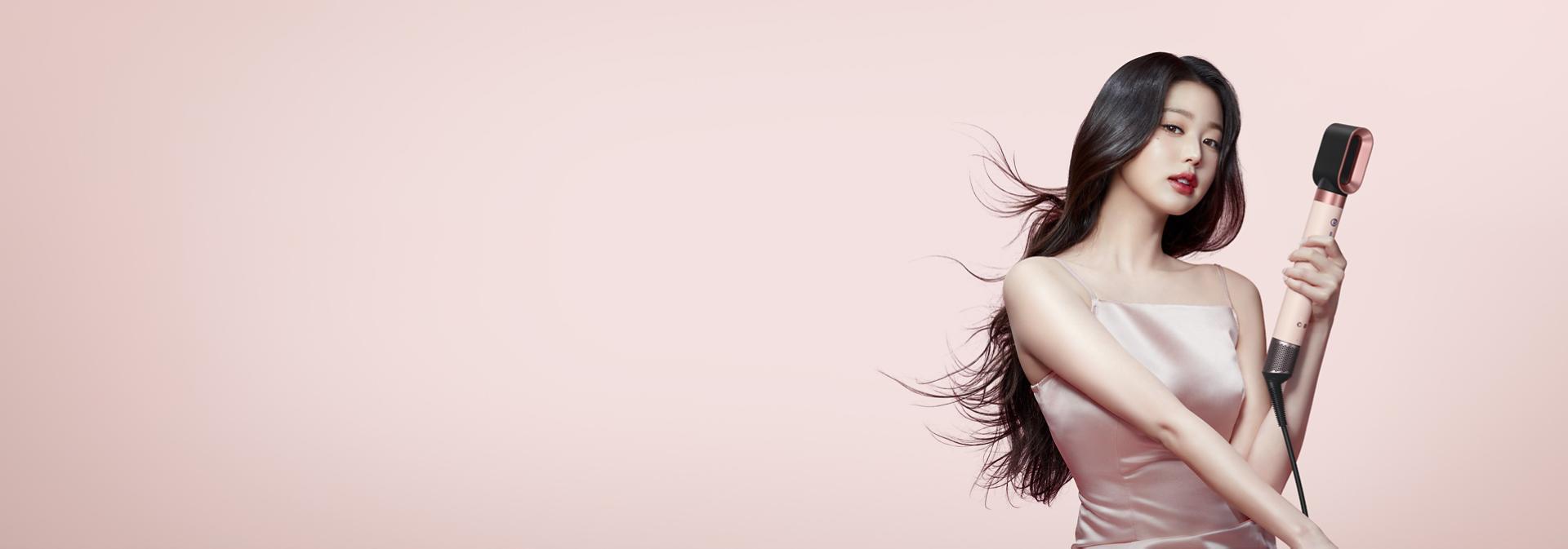 패스트 드라이어 2x가 장착된 다이슨 에어랩 코안다 2x™ 멀티 스타일러 앤 드라이어로 긴 머리를 건조하는 검은색 모발의 모델.