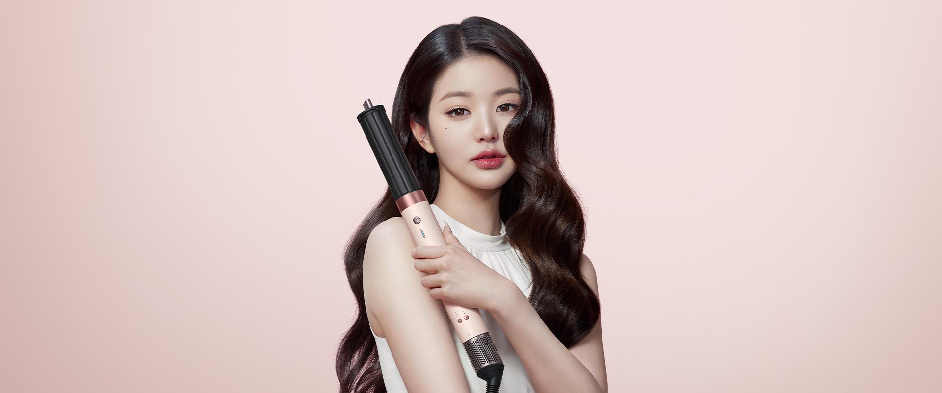 Splitscreen of the Dyson Airwrap Co-anda2x multi-styler and dryer, and a blonde model with hair styled with the device.