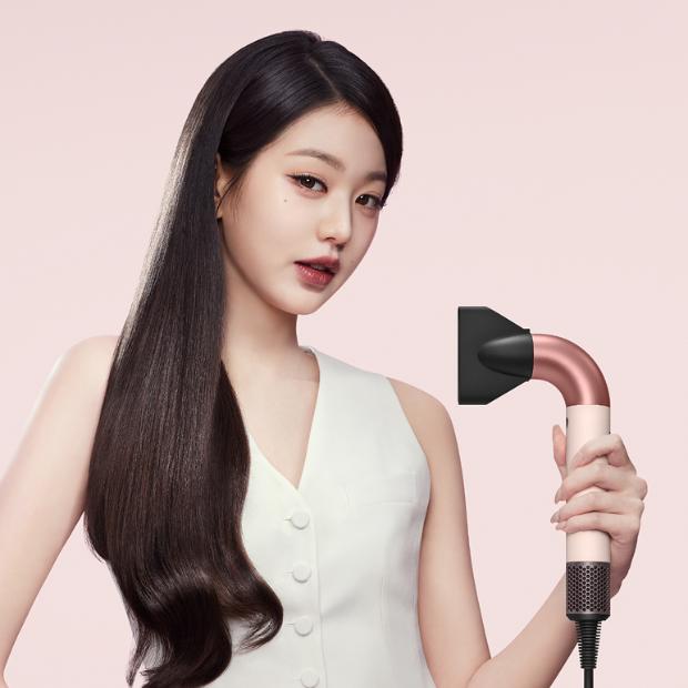 Model mengeringkan rambutnya dengan pengering rambut Dyson Supersonic.