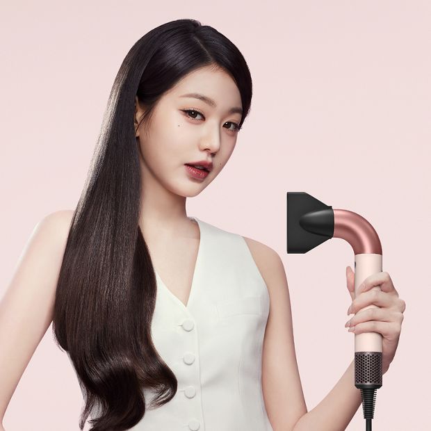 Model mengeringkan rambutnya dengan pengering rambut Dyson Supersonic.