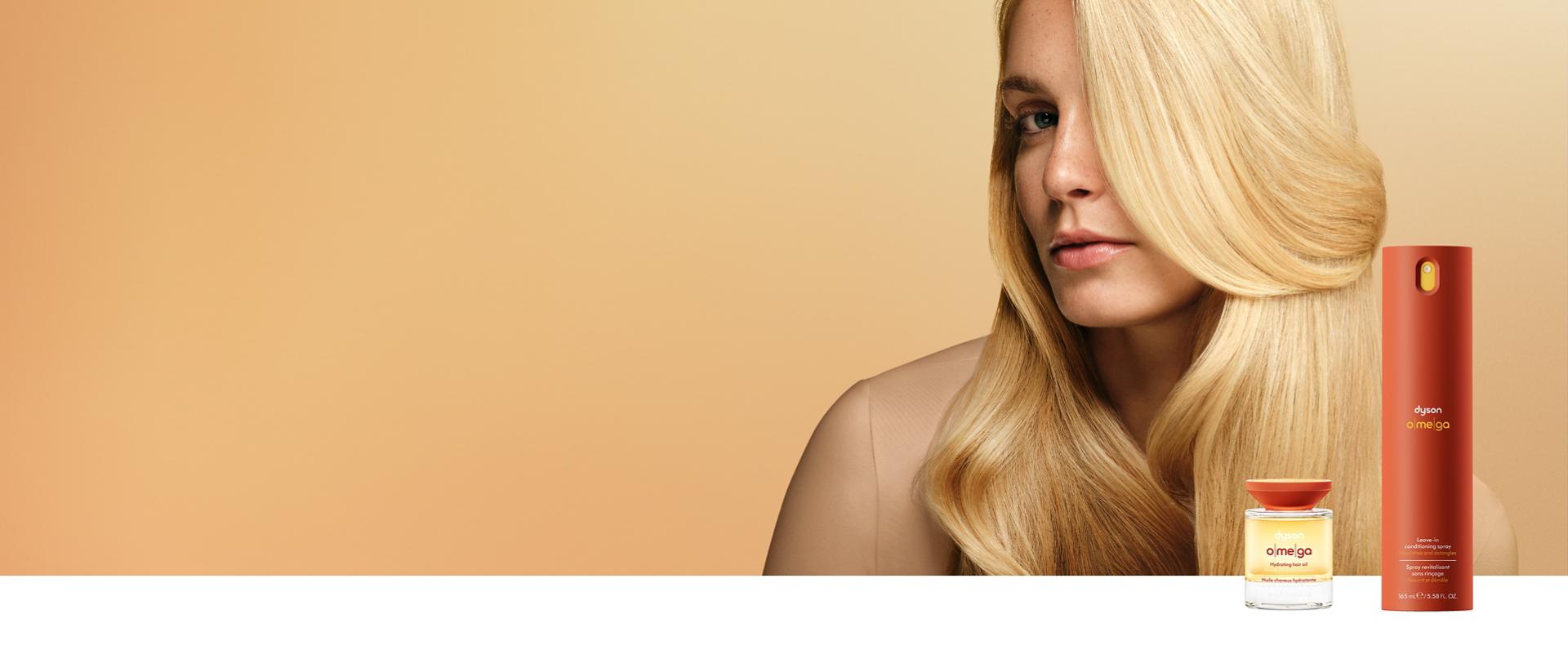 A curly haired model behind the Dyson Omega hair care range.