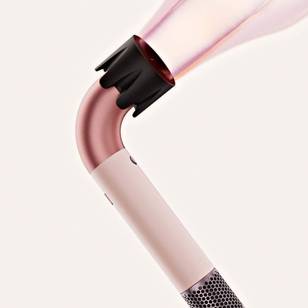 A model styles her hair with the Dyson Supersonic Nural hair dryer and Wave+Curl diffuser.