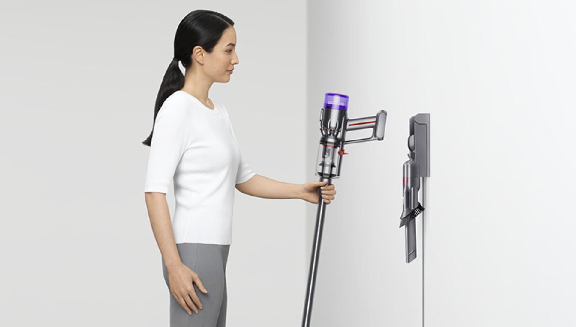 Woman putting a Dyson Micro 1.5kg vacuum into a wall dock