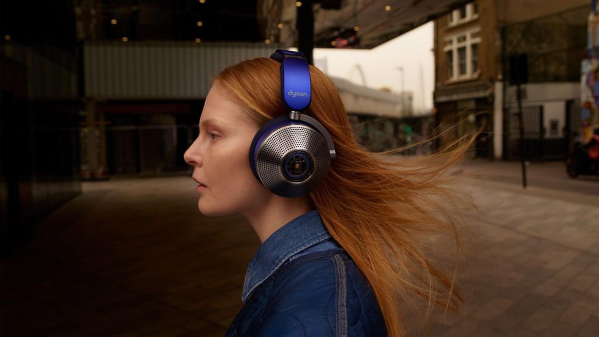 Modelka ubrana w dżinsy i Dyson Zone słuchawki z aktywną redukcją hałasu, spacerująca po mieście.