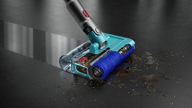 A close-up of a Dyson cordless vacuum cleaner head removing debris from carpet.