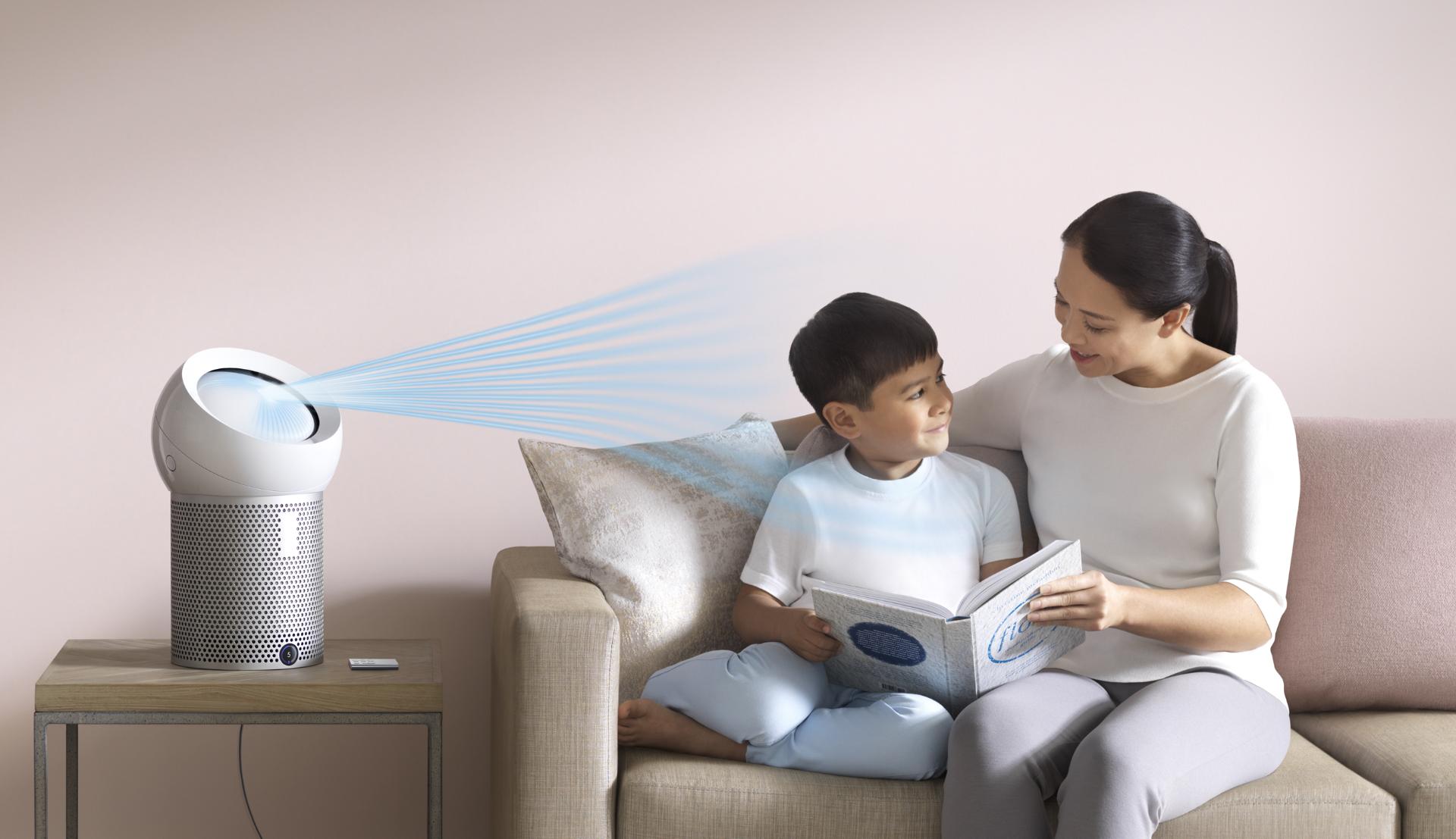 A woman reads to her son, next to a Dyson personal purifier fan