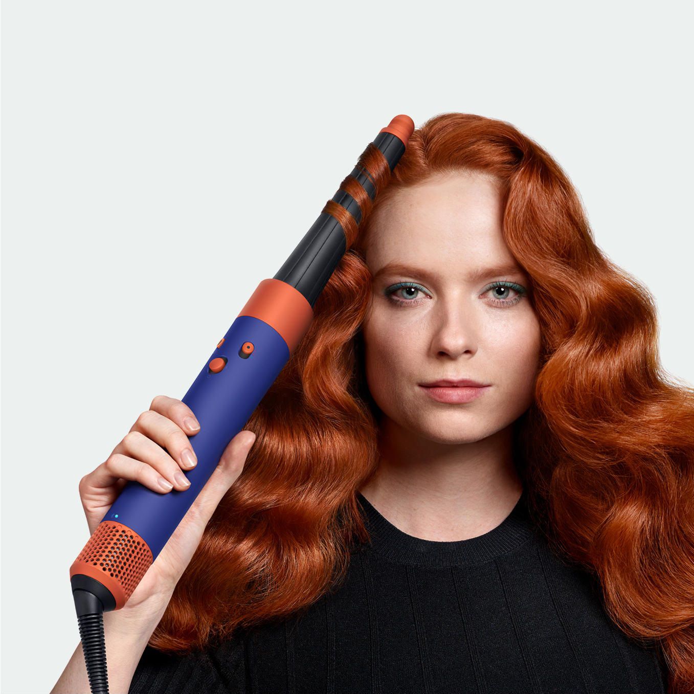 Un model folosește aparatul de coafat și uscătorul Dyson Airwrap ID pentru a-și ondula părul.