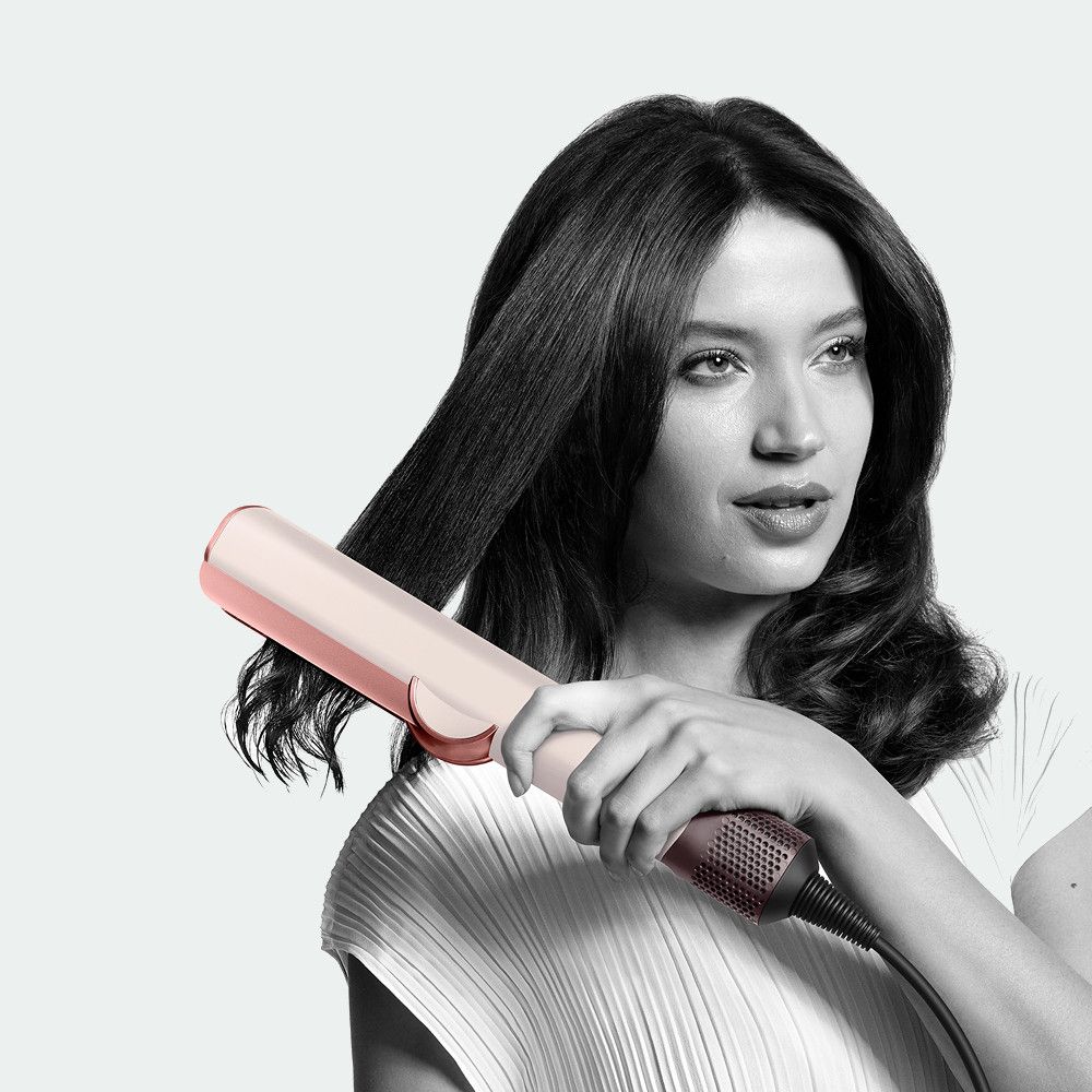Modelka prostuje włosy za pomocą aeroprostownicy Dyson Airstrait.