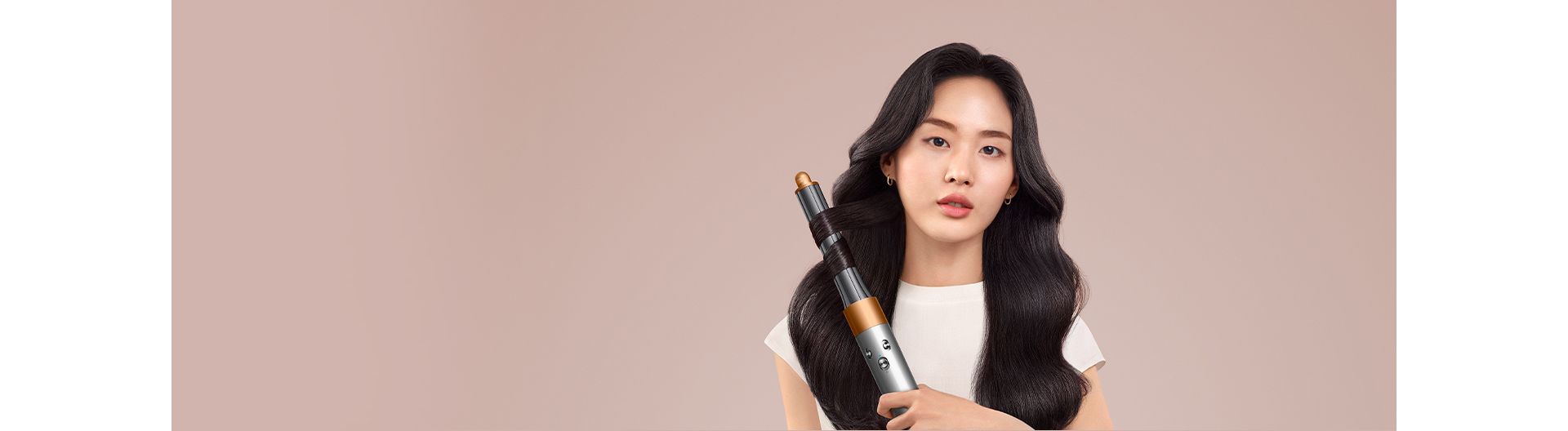 A brunette model smooths flyaways with her Dyson Airwrap Origin multi-styler and dryer.