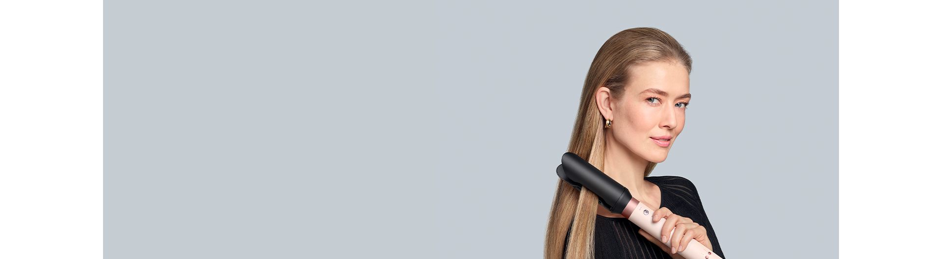 A blonde model straightens her hair using the Dyson Co-anda2x multi-styler and dryer and the AirSmooth2x attachment.