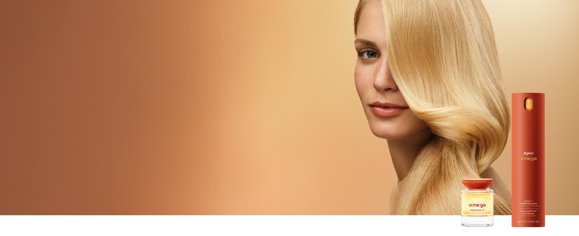 A curly haired model behind the Dyson Omega hair care range.