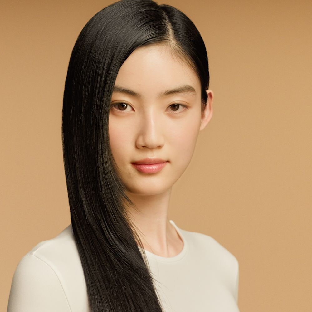 A curly haired model shows off her nourished hair after using Dyson Omega products.