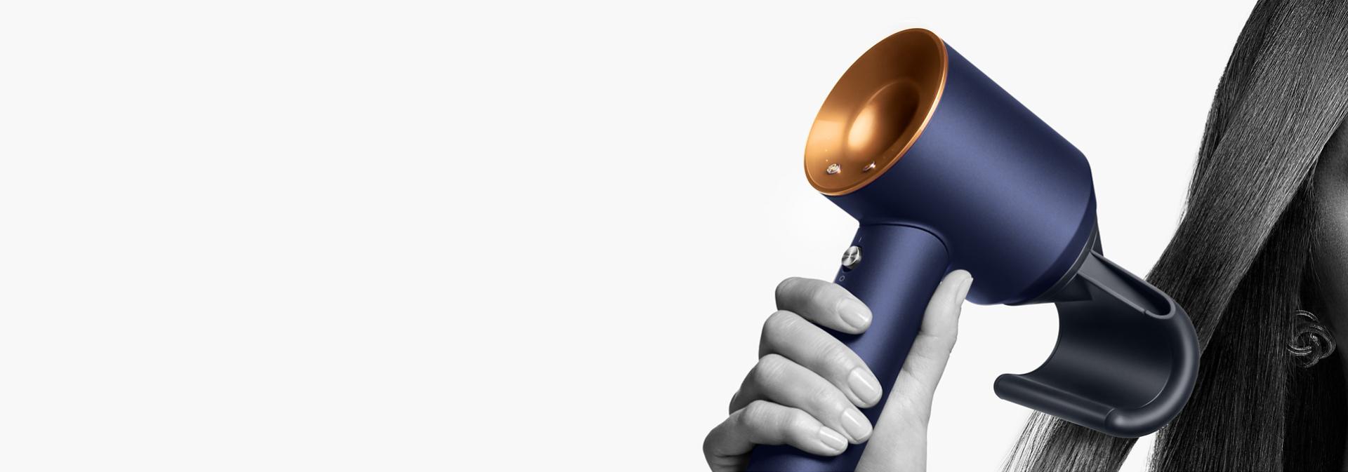 The Dyson Supersonic hair dryer with the Flyaway attachment held by a model.