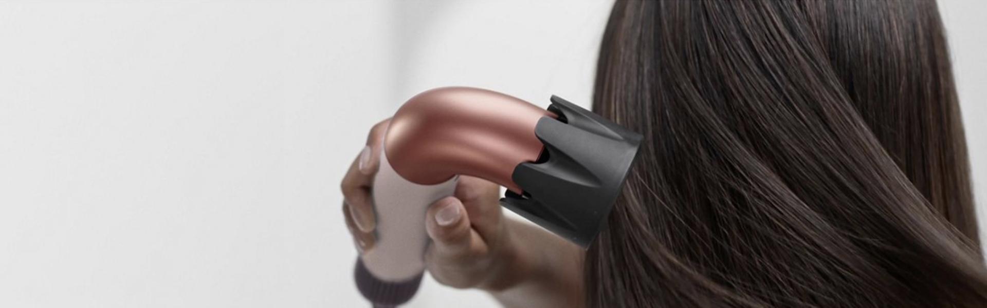 Model dries hair with Dyson Supersonic r Professional hair dryer.