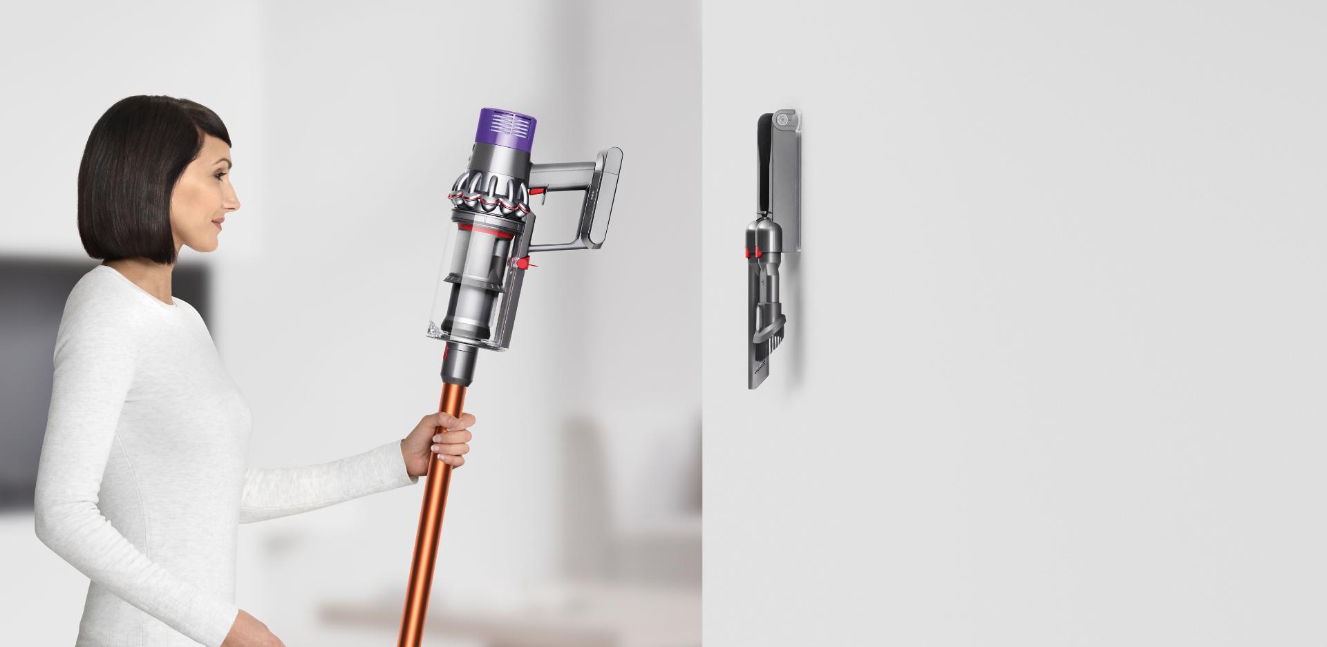 Kadın Dyson Cyclone V10™ elektrikli süpürgeyi yuvasına yerleştirirken