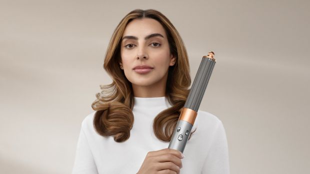 A picture of a woman with wavy, brown hair, holding the Dyson Airwrap