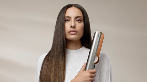 A picture of a woman with straight, brown hair, holding the Dyson Airstrait