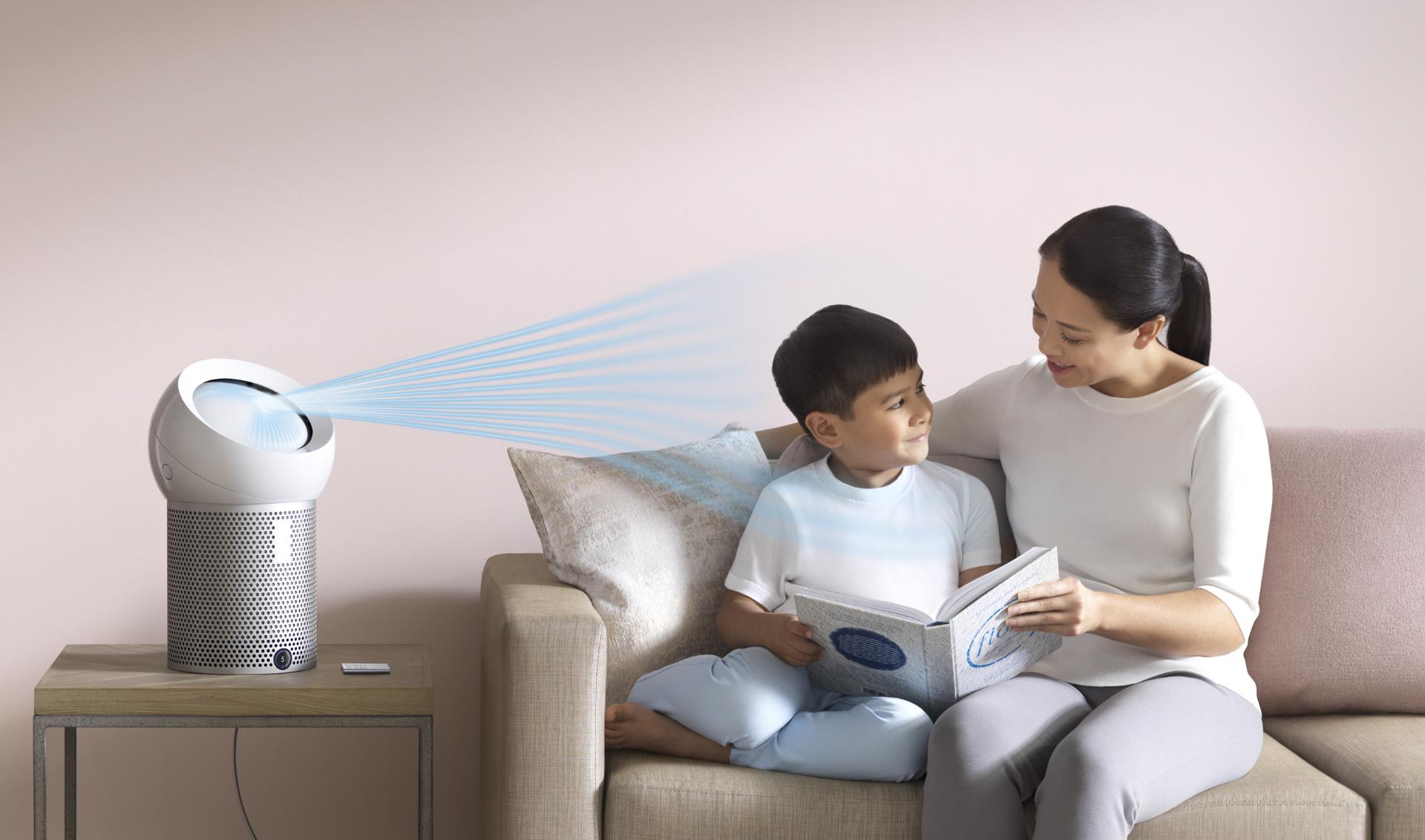 فتى يقرأ كتاباً في فراشه بينما تقوم مروحة دايسون المُنقية الشخصية بضخ تيار هواء بارد تجاهه.