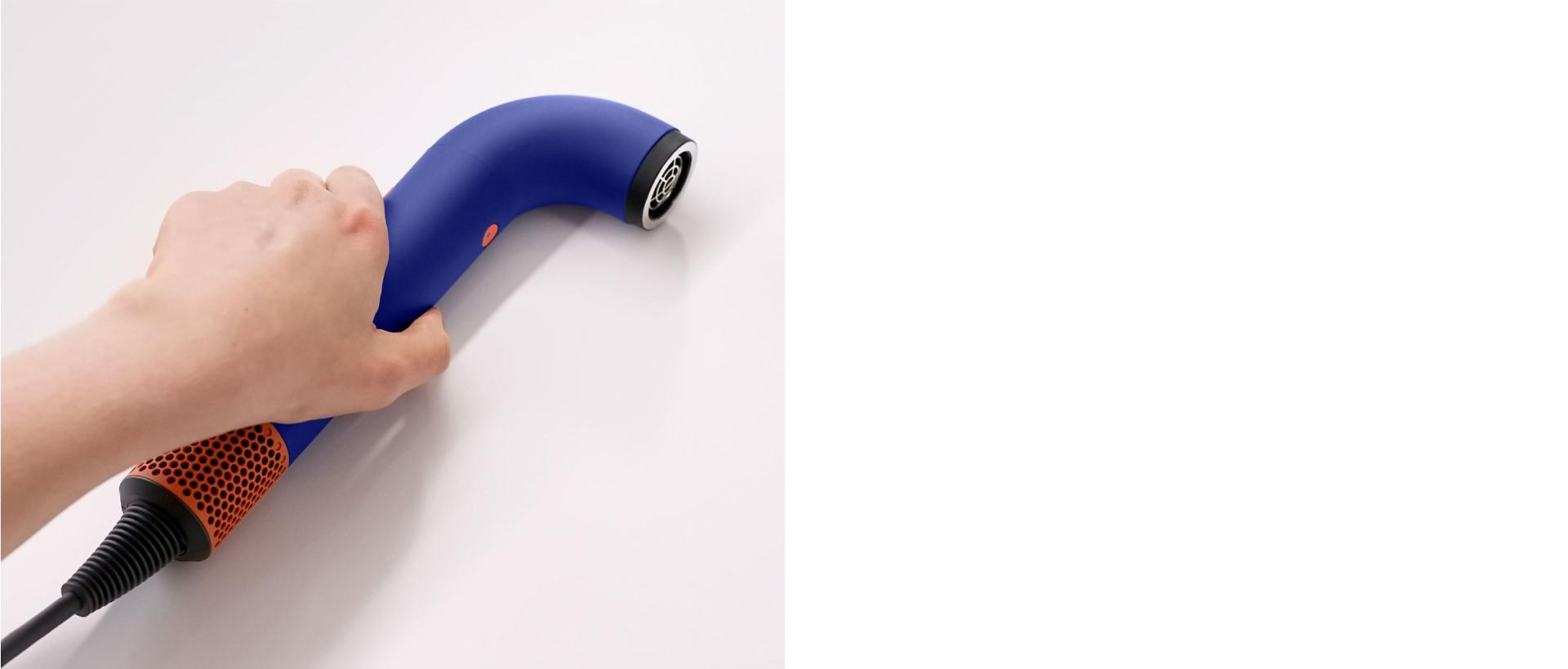 Hand picking up the Dyson Supersonic r hair dryer.