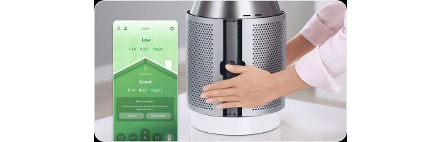 Owner fitting the filter shroud back onto their Dyson purifier with the MyDyson app reporting their air quality.