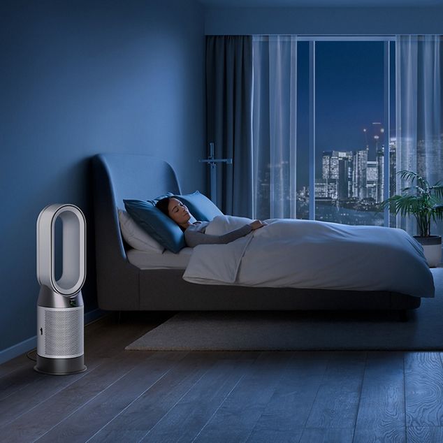 A Dyson purifier in a bedroom, purifying air at night while a person sleeps