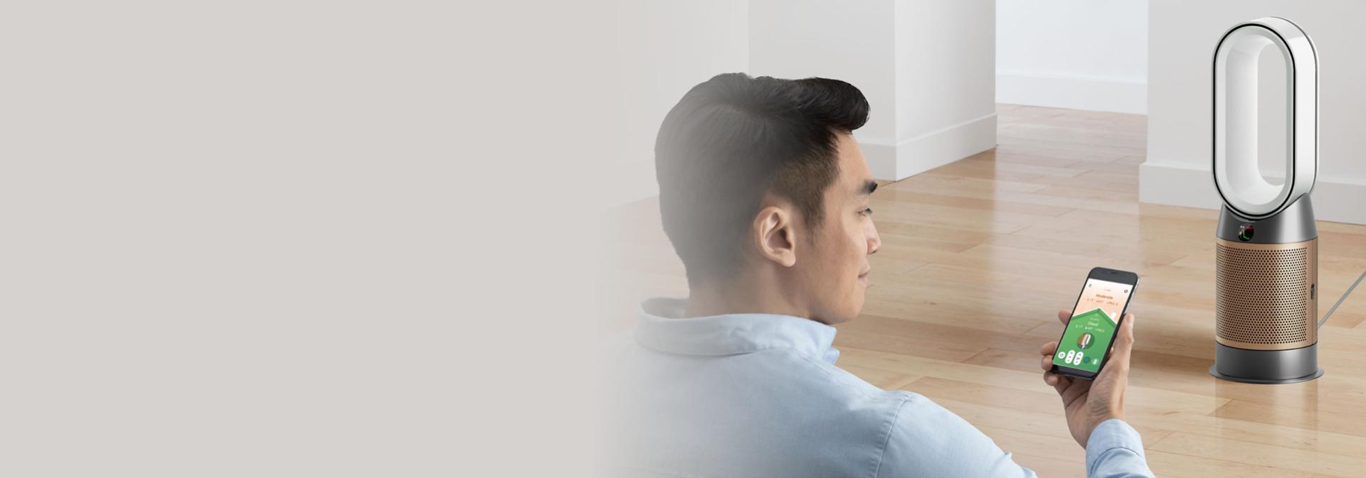 Akıllı telefonununu kullanarak hava kalitesini görüntüleyip kontrol eden bir ürün sahibi.