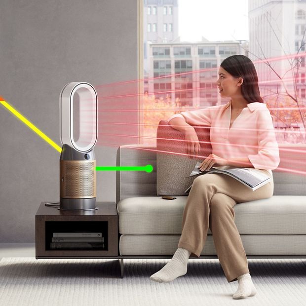 A person sitting on a sofa while a purifier heater projects warm air.