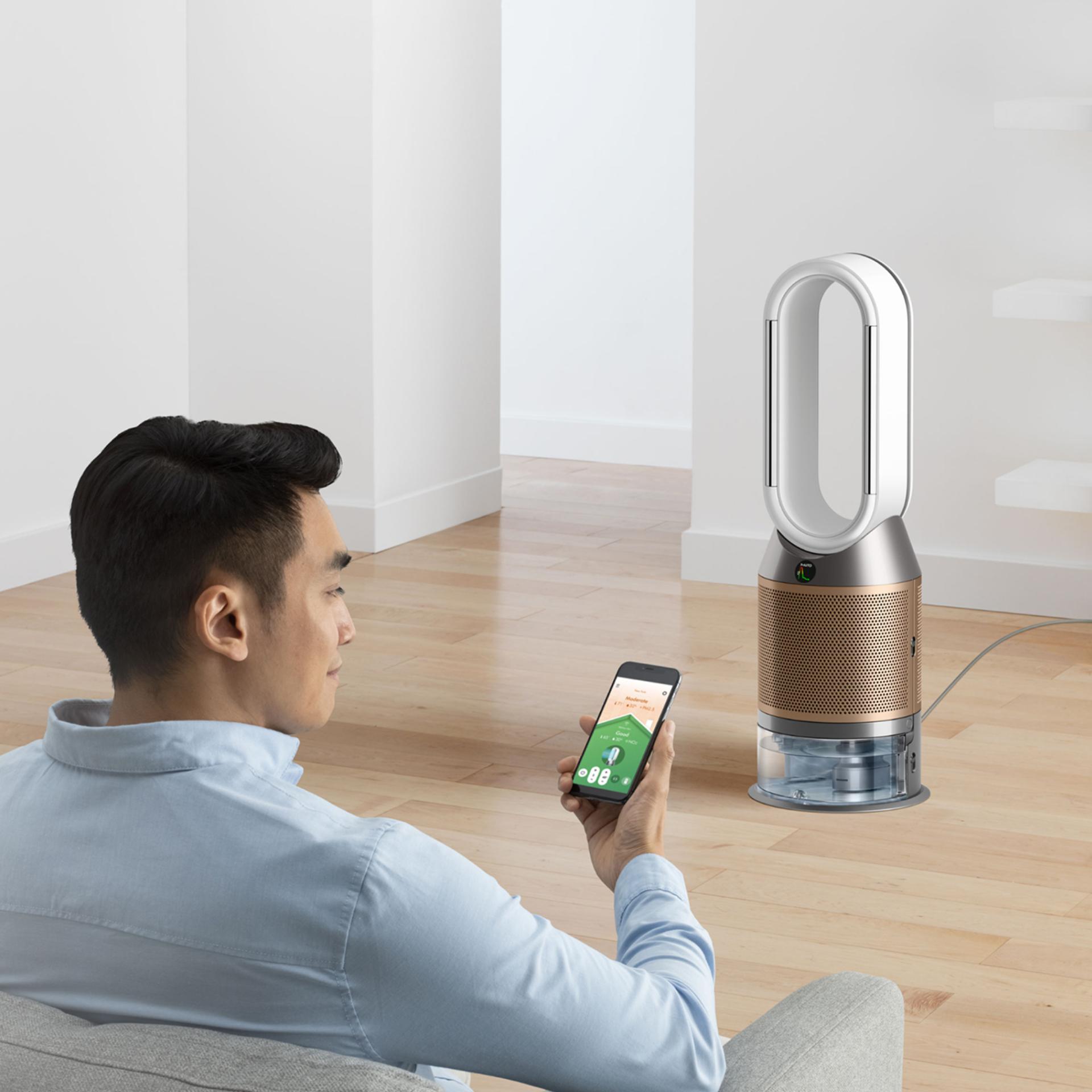 A person using the app on their phone with a purifier in the background