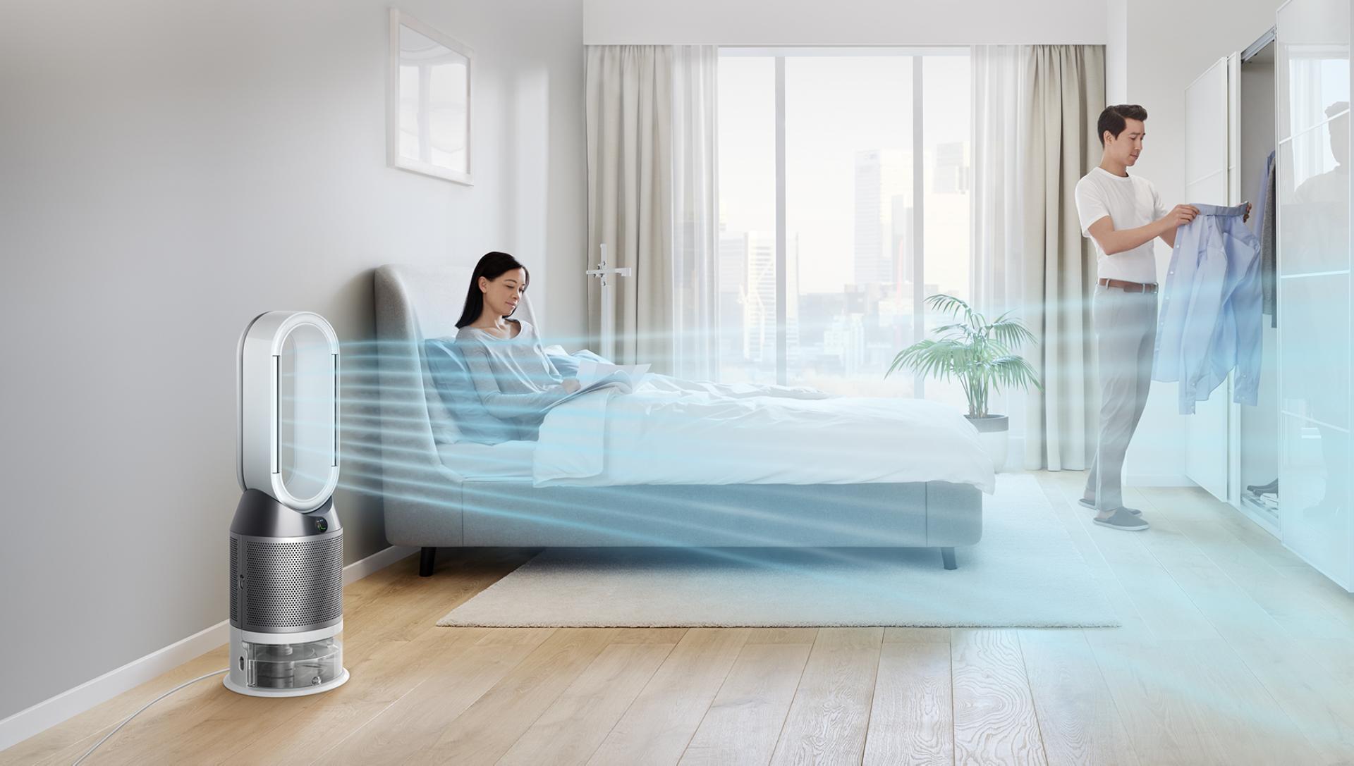 A woman relaxes in bed while her Dyson purifier humidifier fan circulates air through the room