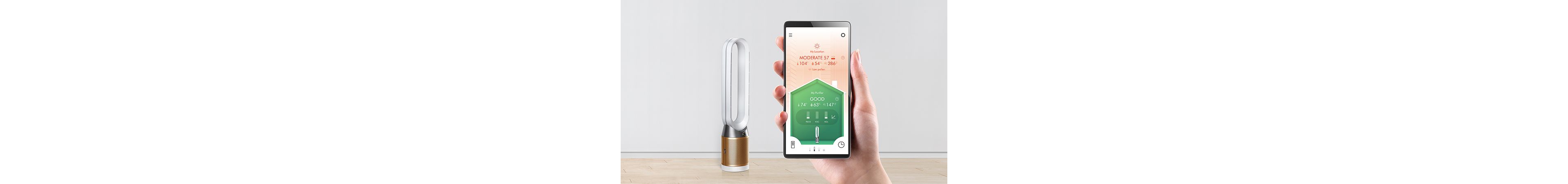 A hand holding up a smart phone in front of a Dyson purifier. The phone screen displays the Dyson Link app. 