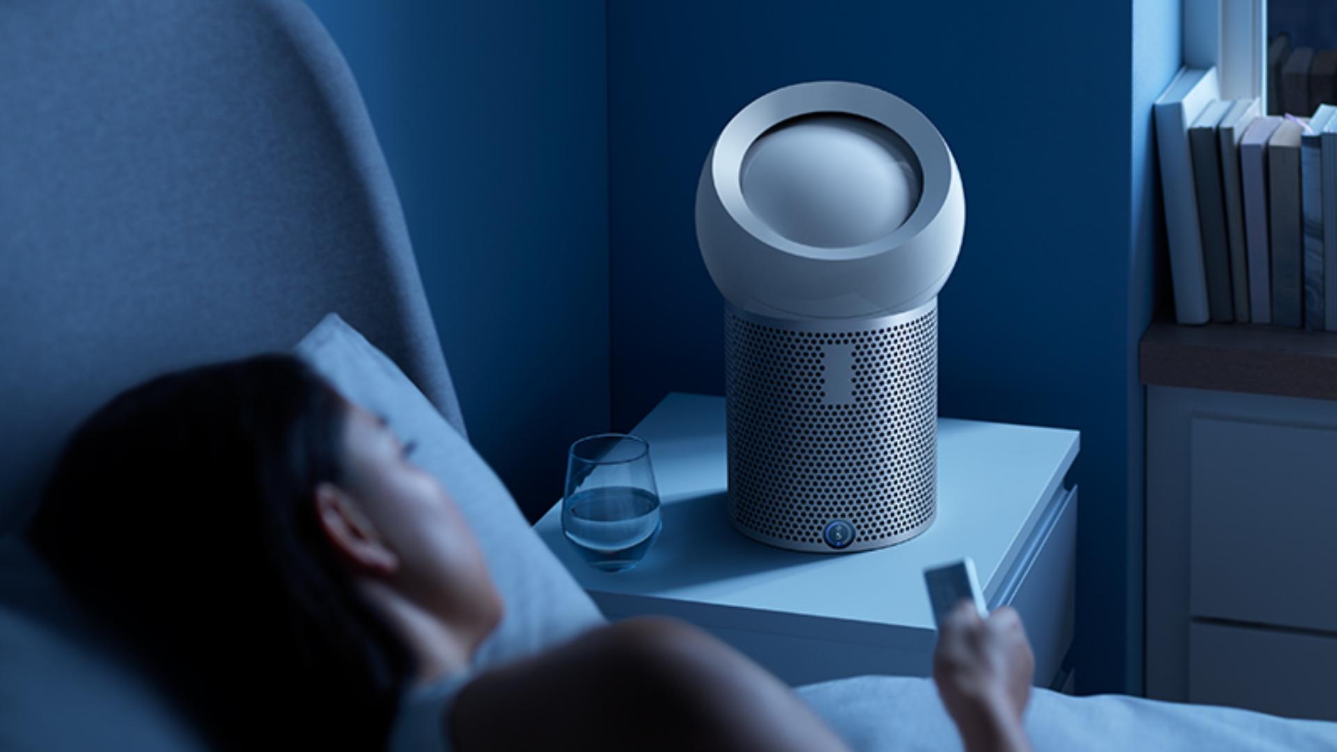 一位女士在床上使用無線遙控來設定個人空氣淨化風扇的睡眠定時器